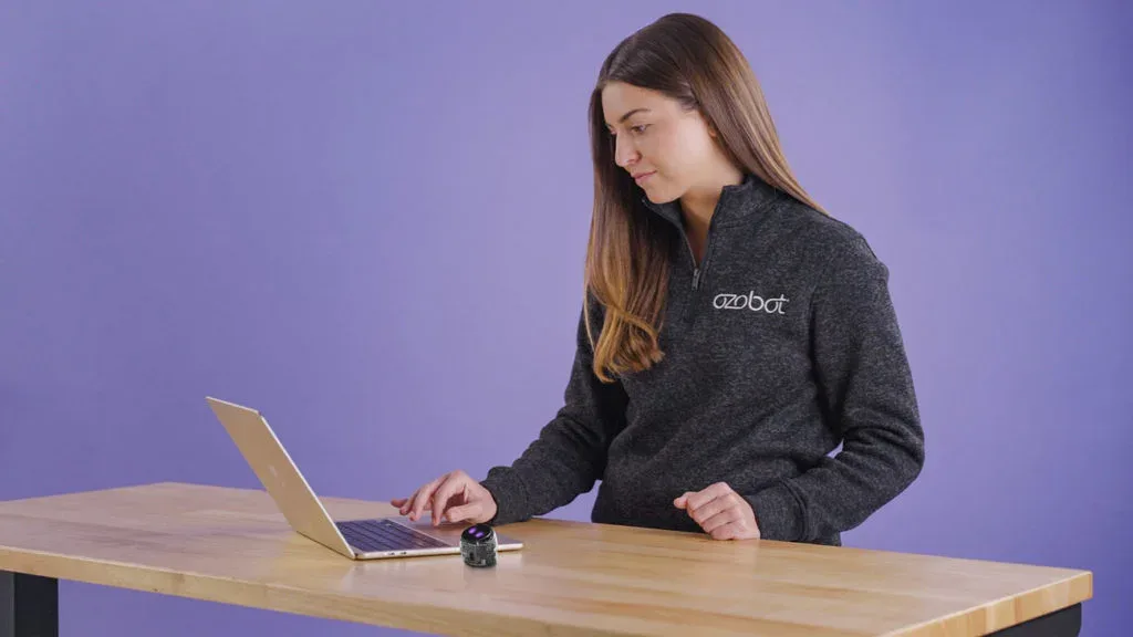 Docent programmeert Ari met een laptop